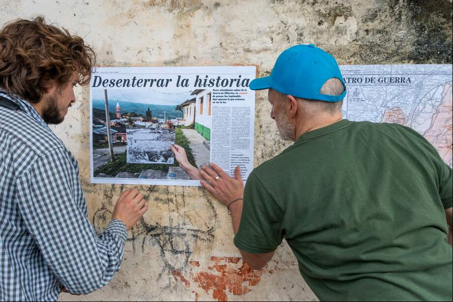Stephen Ferry (derecha) Y Tomás Mantilla, coautor, pegan la primera página del informe La Época en una de las paredes de la escuela vocacional de La Colonia, abandonada tras la guerra.